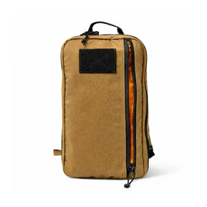 Tan tactical backpack with an open orange-lined zipper pocket and a black patch.
