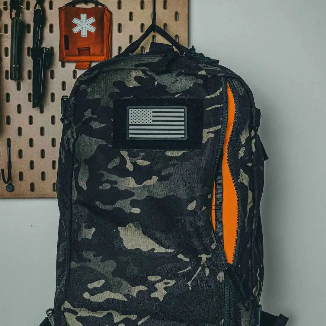 Camouflage backpack with American flag patch and orange interior visible