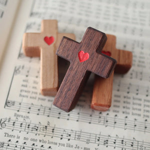 Wooden crosses with red hearts sit on sheet music.