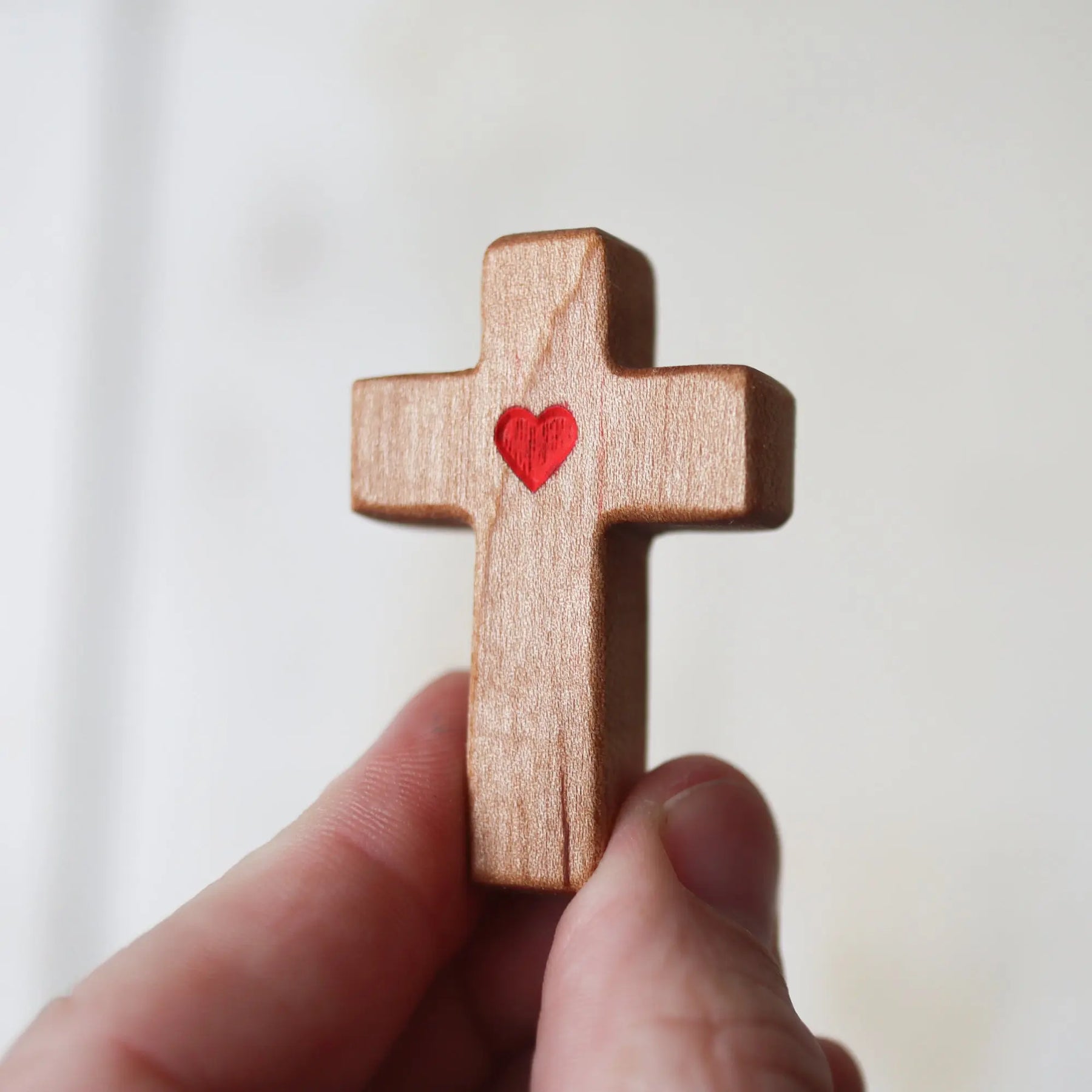 Agape Pocket Crosses wooden cross with carved red heart inlay held in hand