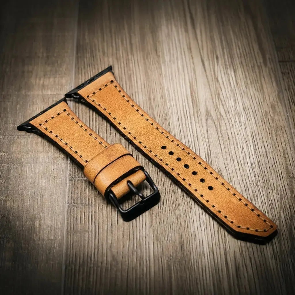 Leather Apple Watch band with black buckle on a wooden surface.