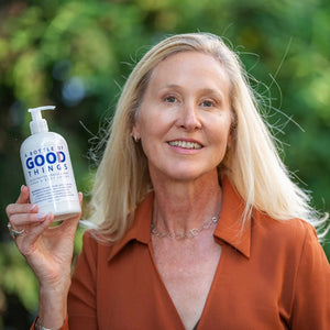 Woman holding Arnica + Mint Hand & Body Lotion bottle.
