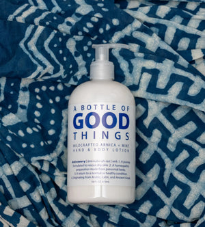 White pump lotion bottle with blue text, 'Arnica Mint Hand & Body Lotion', on blue patterned cloth.