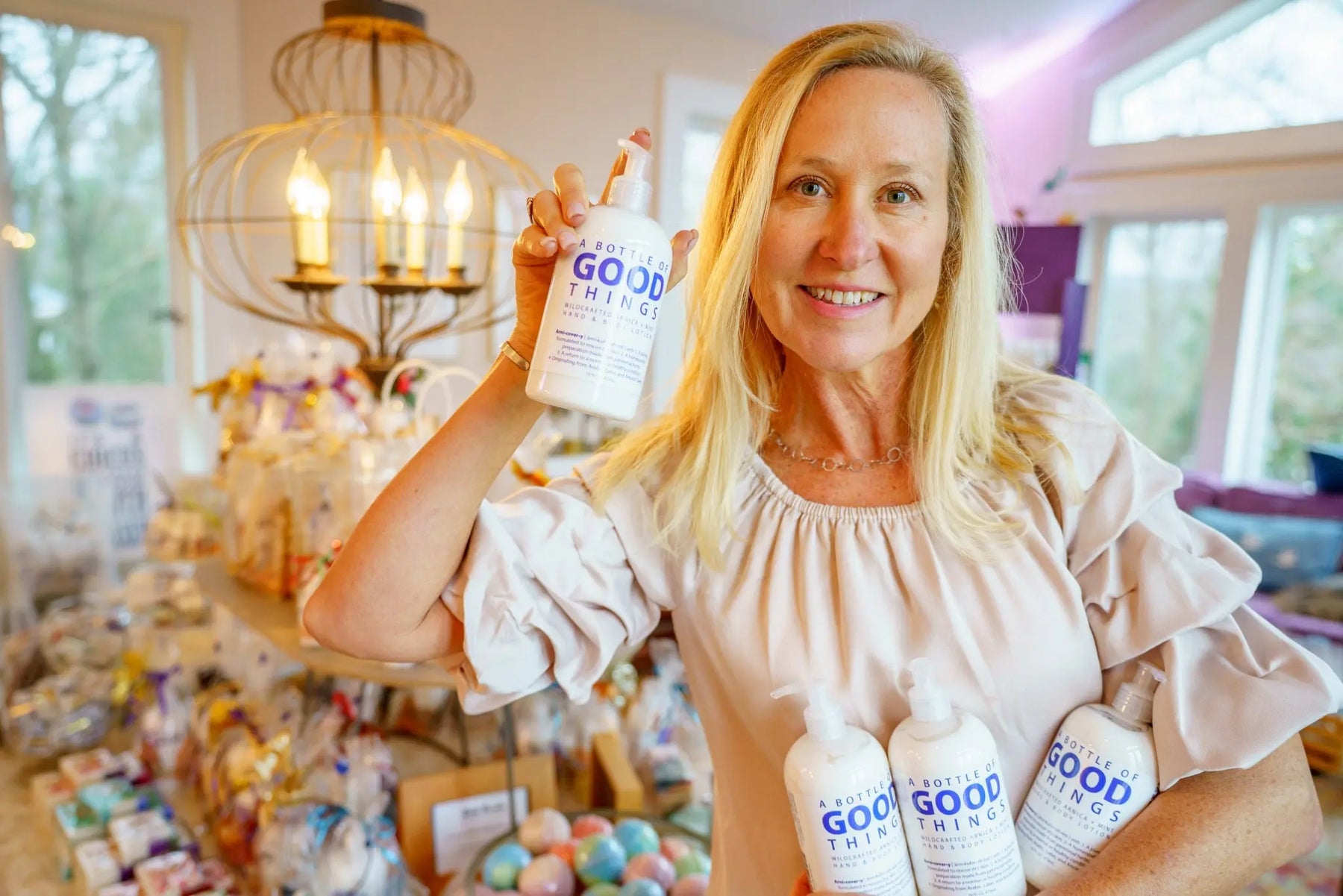 Woman holding a pump bottle of Arnica + Mint hand and body lotion in a store.