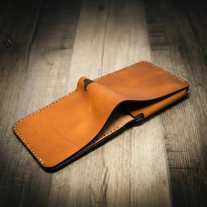 Tan leather bifold wallet folded open on a wooden table.