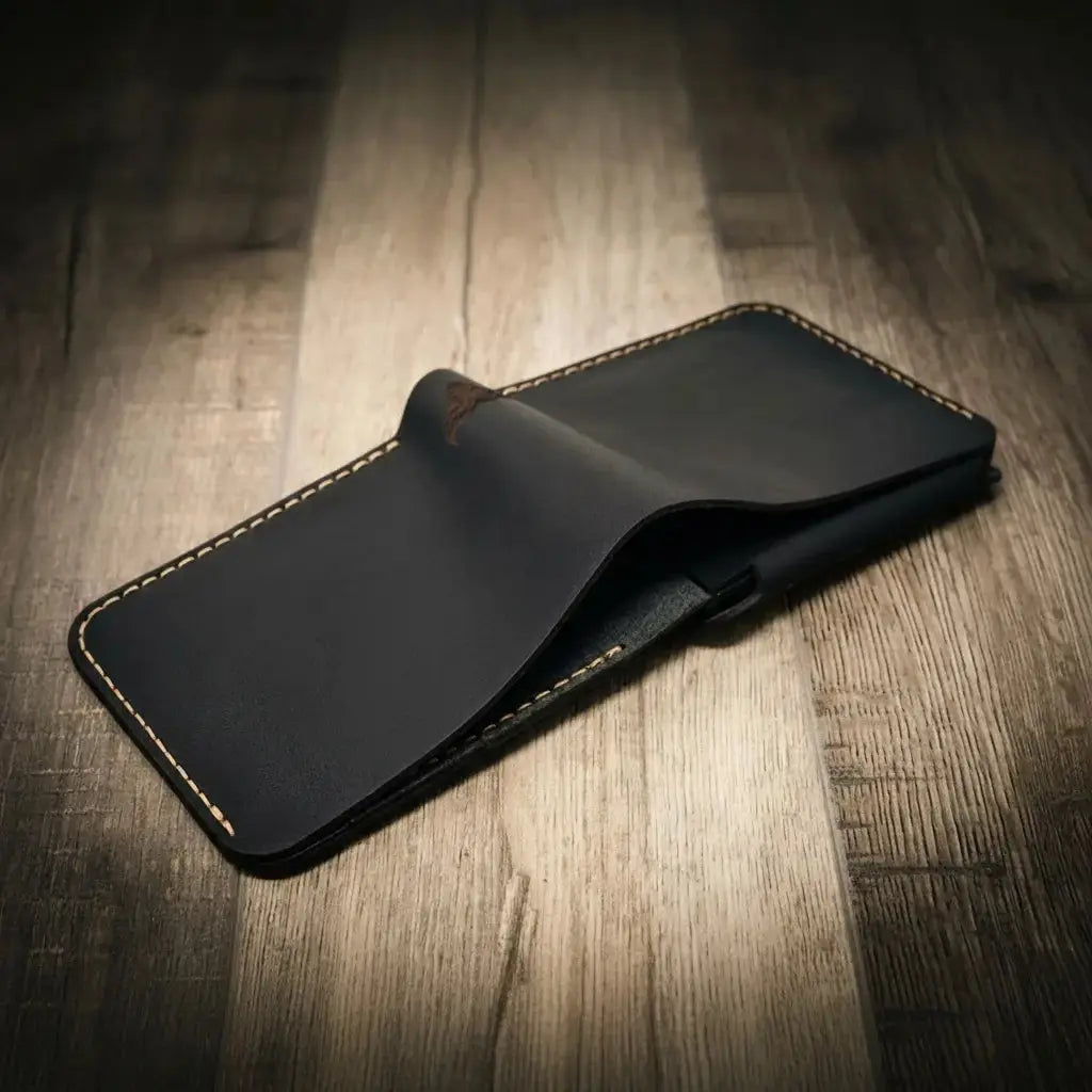 Dark leather bifold wallet with contrast stitching, shown open on a wooden surface.