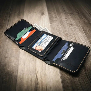 Black leather trifold wallet with ID window, cards, and cash on a wooden surface.