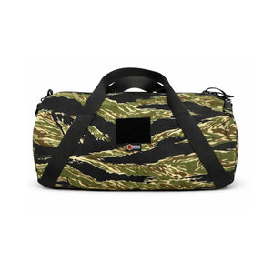 Camouflage barrel duffle bag with black handles and a square patch on the front.