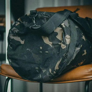 Black and tan camouflage duffle bag with black strap and metal clip.