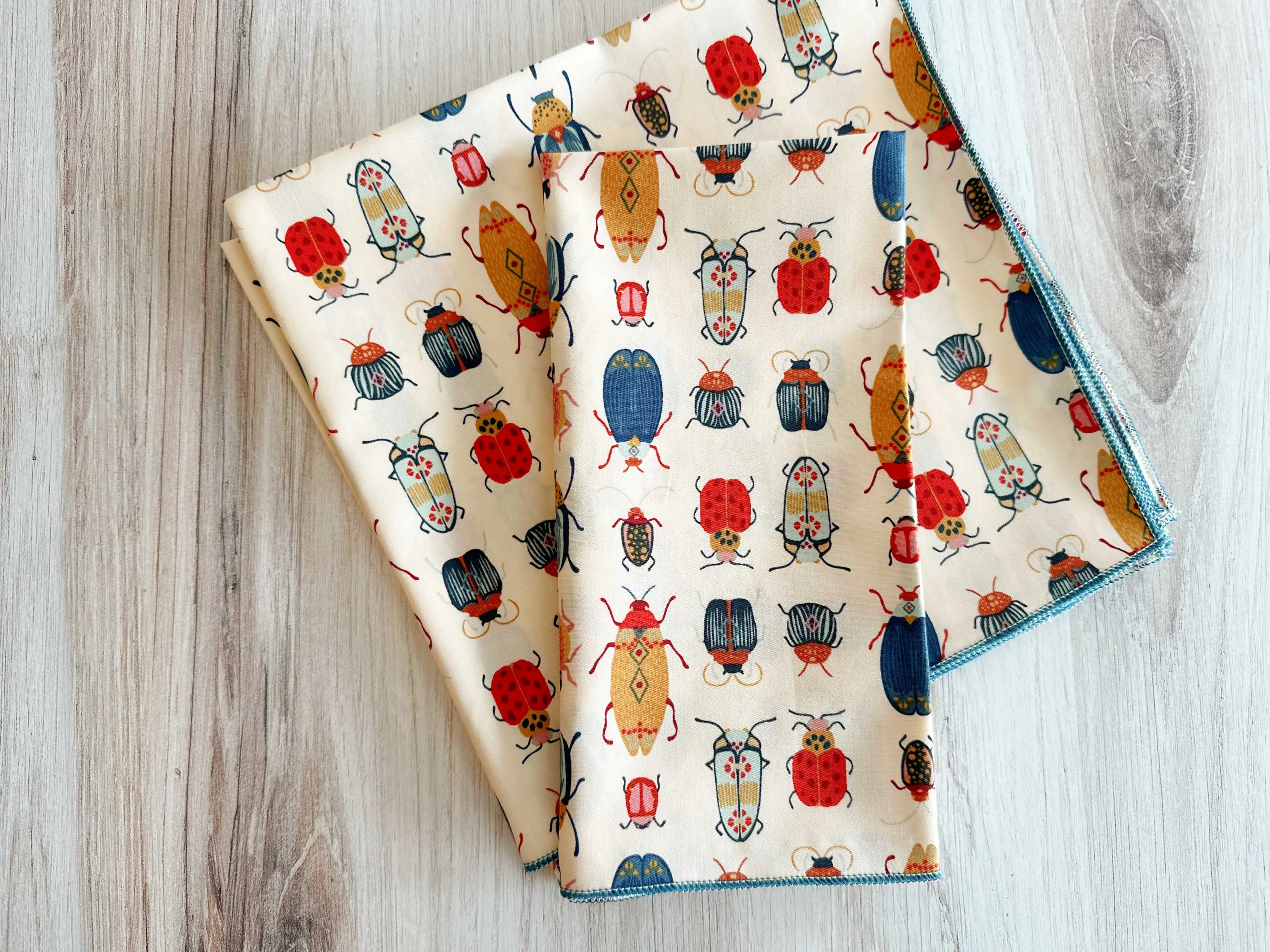 Cream fabric napkins with a pattern of colorful beetles