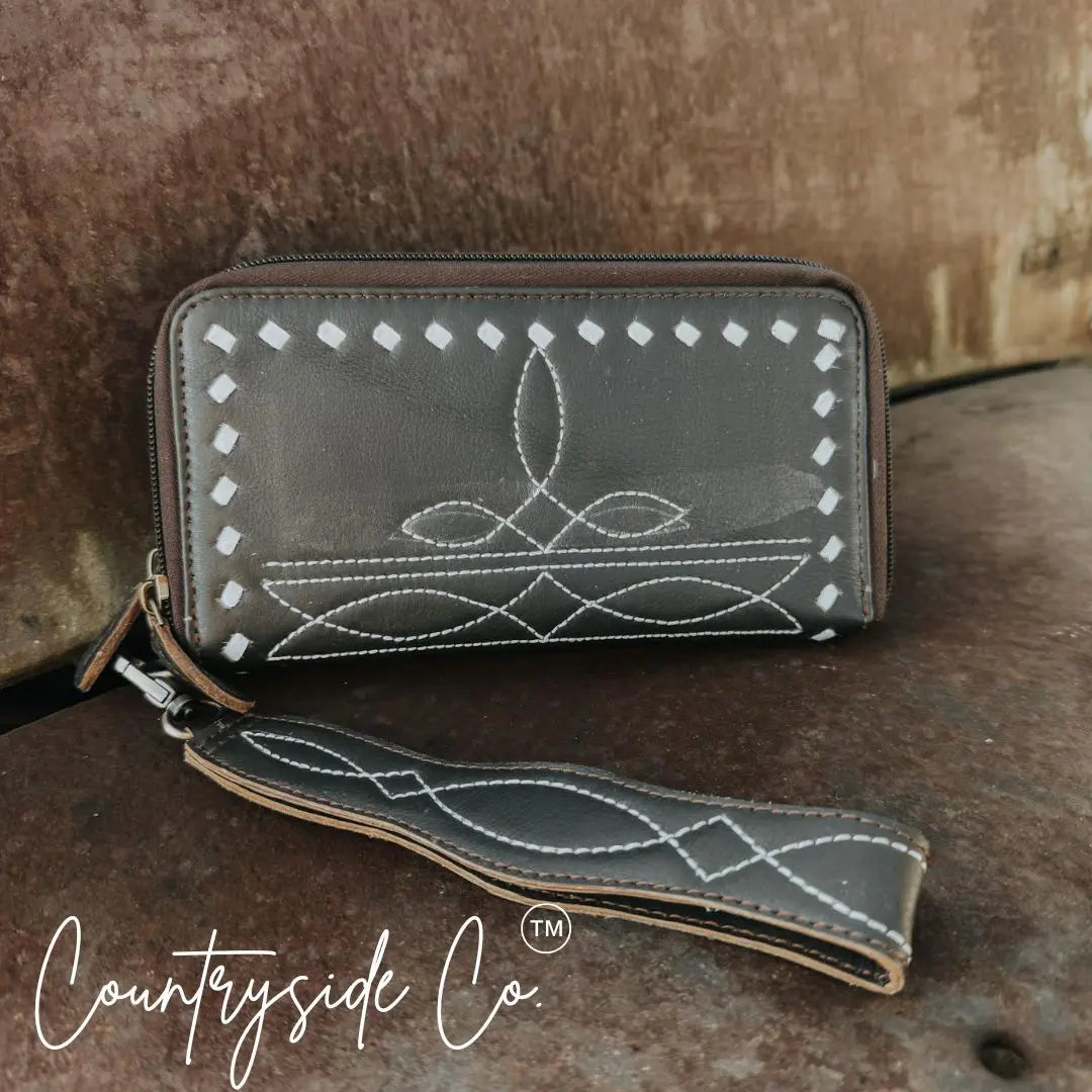Dark brown leather wallet wristlet with white decorative stitching and zipper.