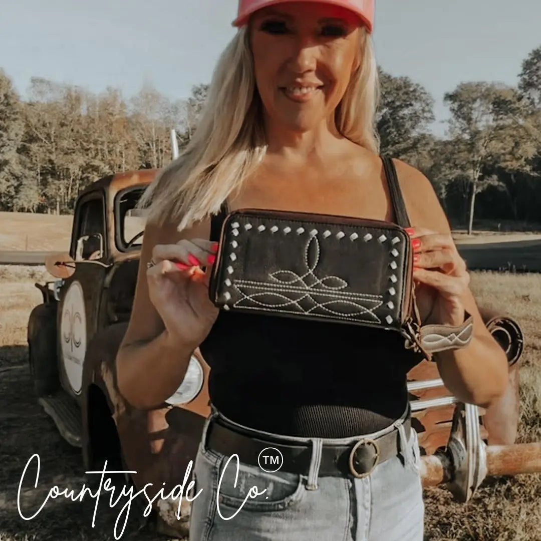 Black leather wallet wristlet with boot stitch embroidery and white decorative stitching.