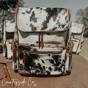 Boulder cowhide backpack with leather trim and multiple zippered pockets.