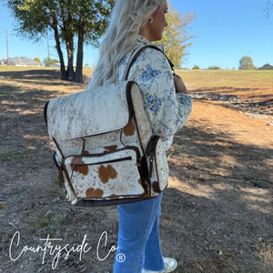 Cowhide conceal carry backpack worn by a person with a floral jacket and jeans.