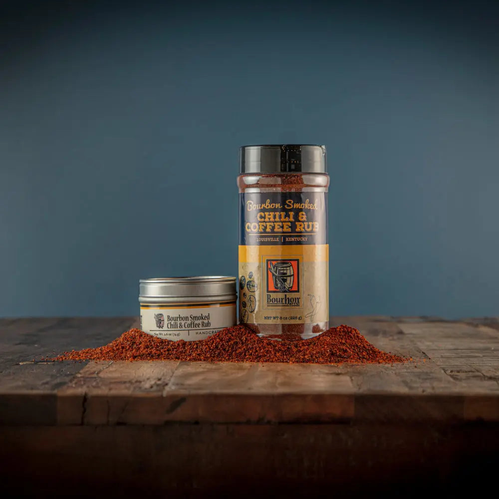 Bourbon Smoked Chili & Coffee Rub in tin and jar with spilled spice on wood.