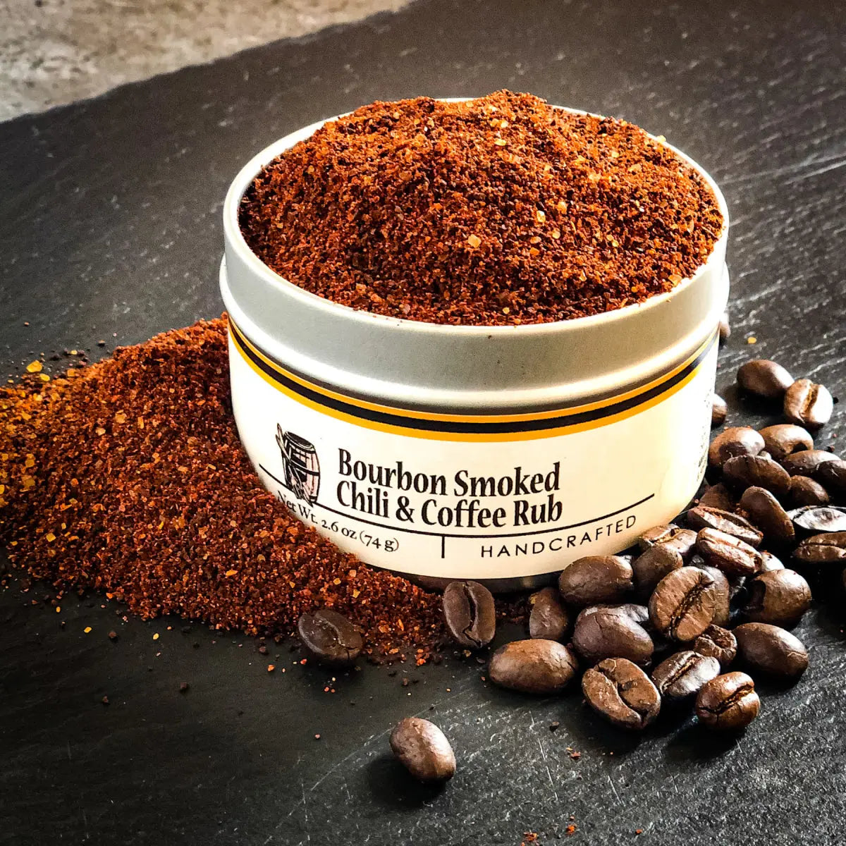 Bourbon smoked chili and coffee rub spilling from a tin with coffee beans.