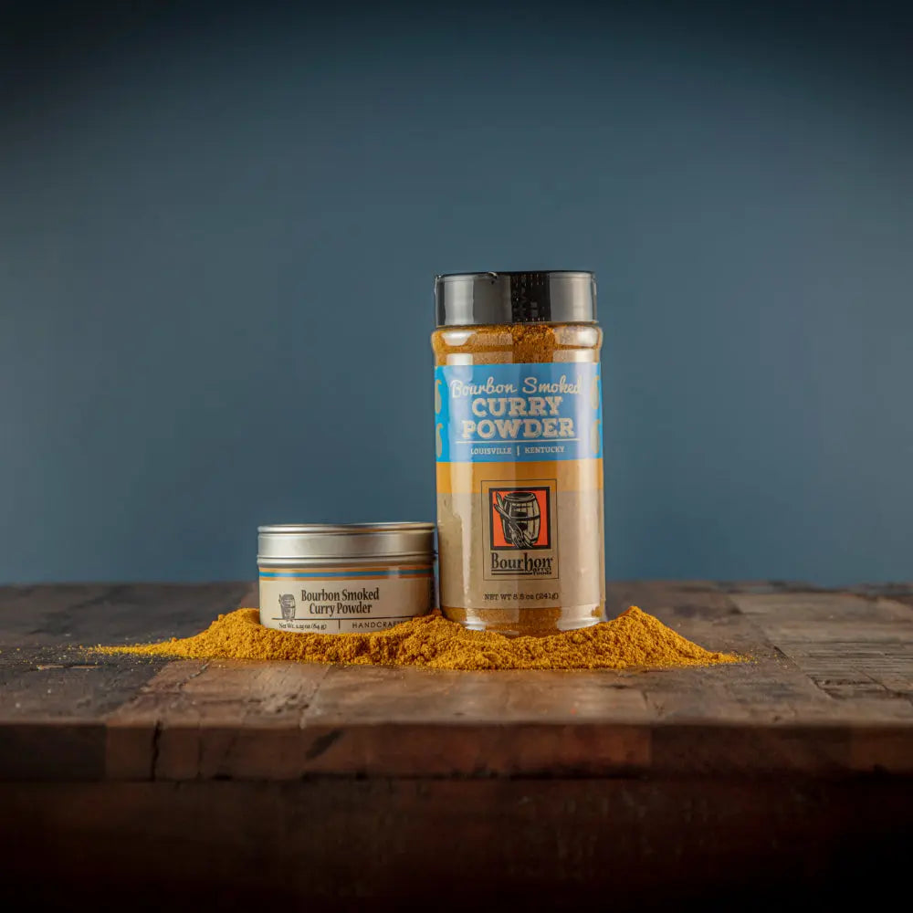 Bourbon Smoked Curry Powder in tin and shaker with spilled curry powder