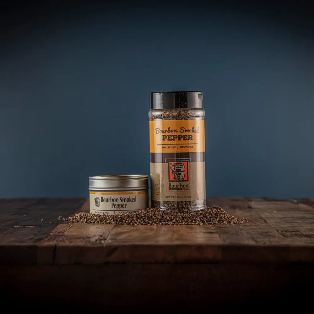 Two jars of Bourbon Smoked Pepper spice on a wooden surface.