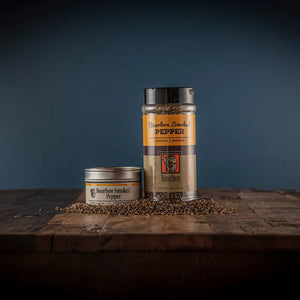 Two jars of Bourbon Smoked Pepper spice on a wooden surface.