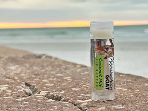 The Appalachian Goat Coconut Milk Lip Butter on a beach with ocean background.