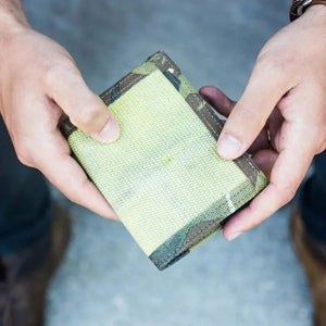 Person holding a camouflage and tan canvas wallet.