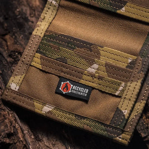 Multicam camouflage wallet with a black logo tag featuring a flame and text.