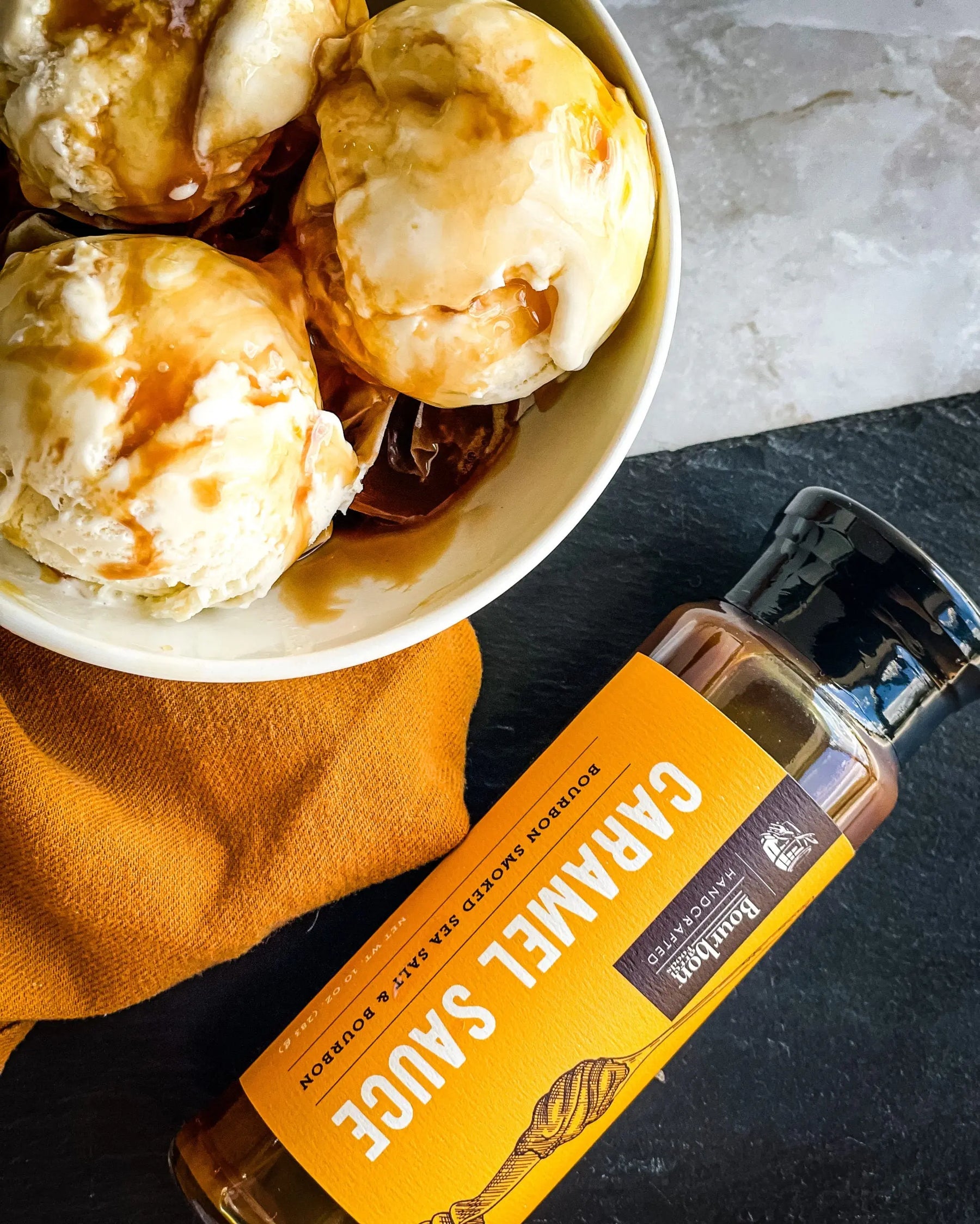 Caramel sauce bottle next to ice cream in a bowl.