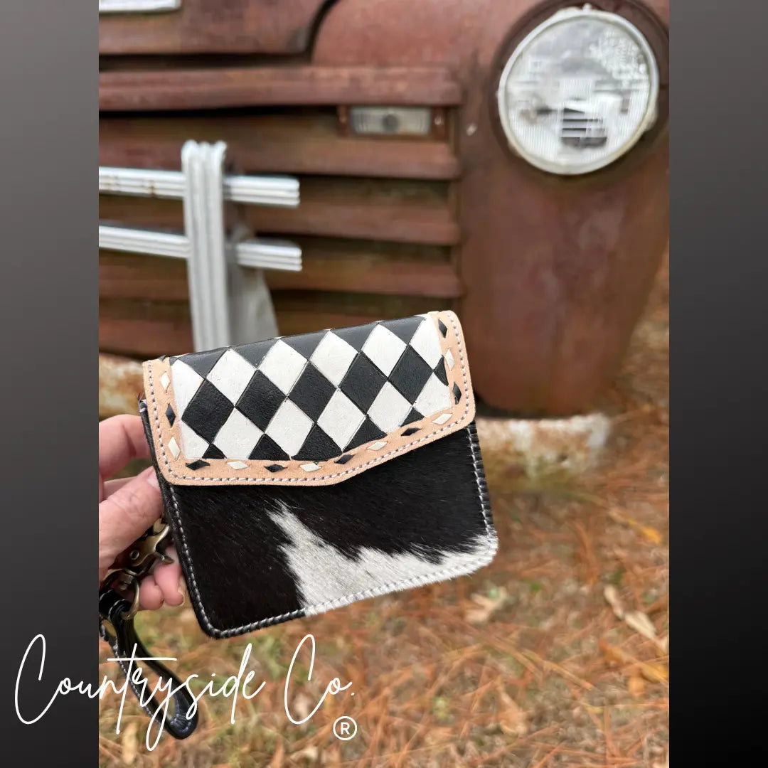 Black and white cowhide wallet wristlet with a checkered flap.