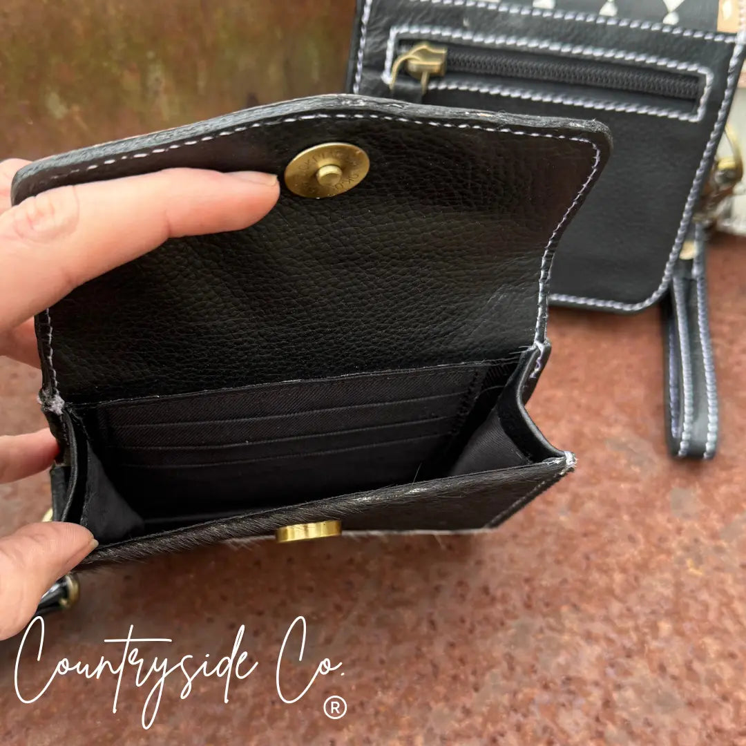 Black leather wallet with cowhide accents and gold snaps, showing interior card slots.
