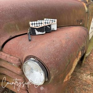 Cassie Checkered Wallet Wristlet with cowhide and checkered pattern on a rusty truck.