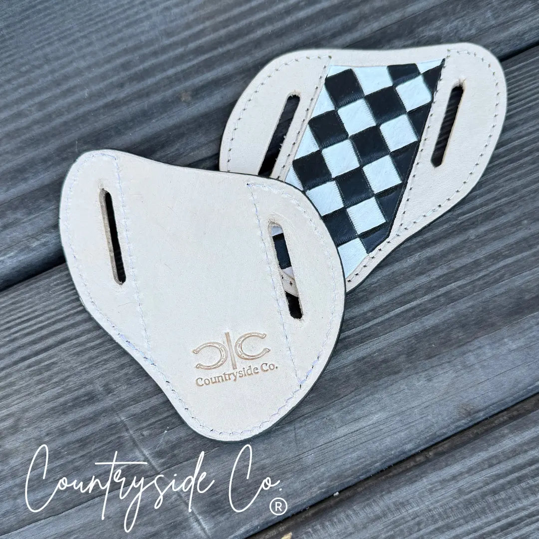 Checkered leather knife sheath with Countryside Co. logo on wooden background