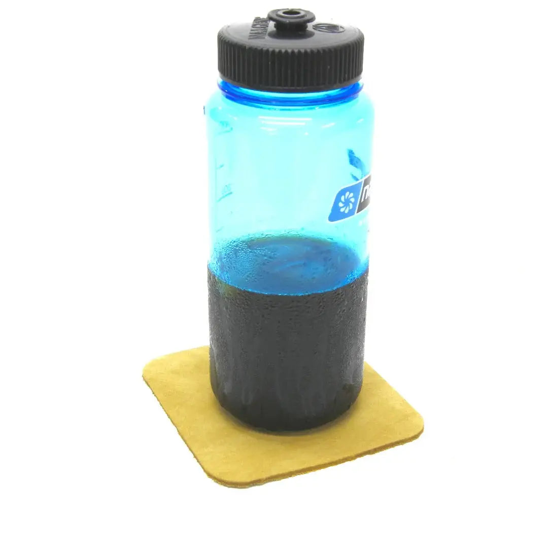 Blue water bottle with dark liquid on yellow coaster