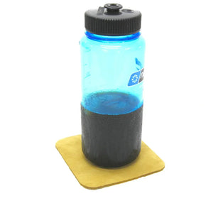 Blue water bottle with dark liquid on yellow coaster