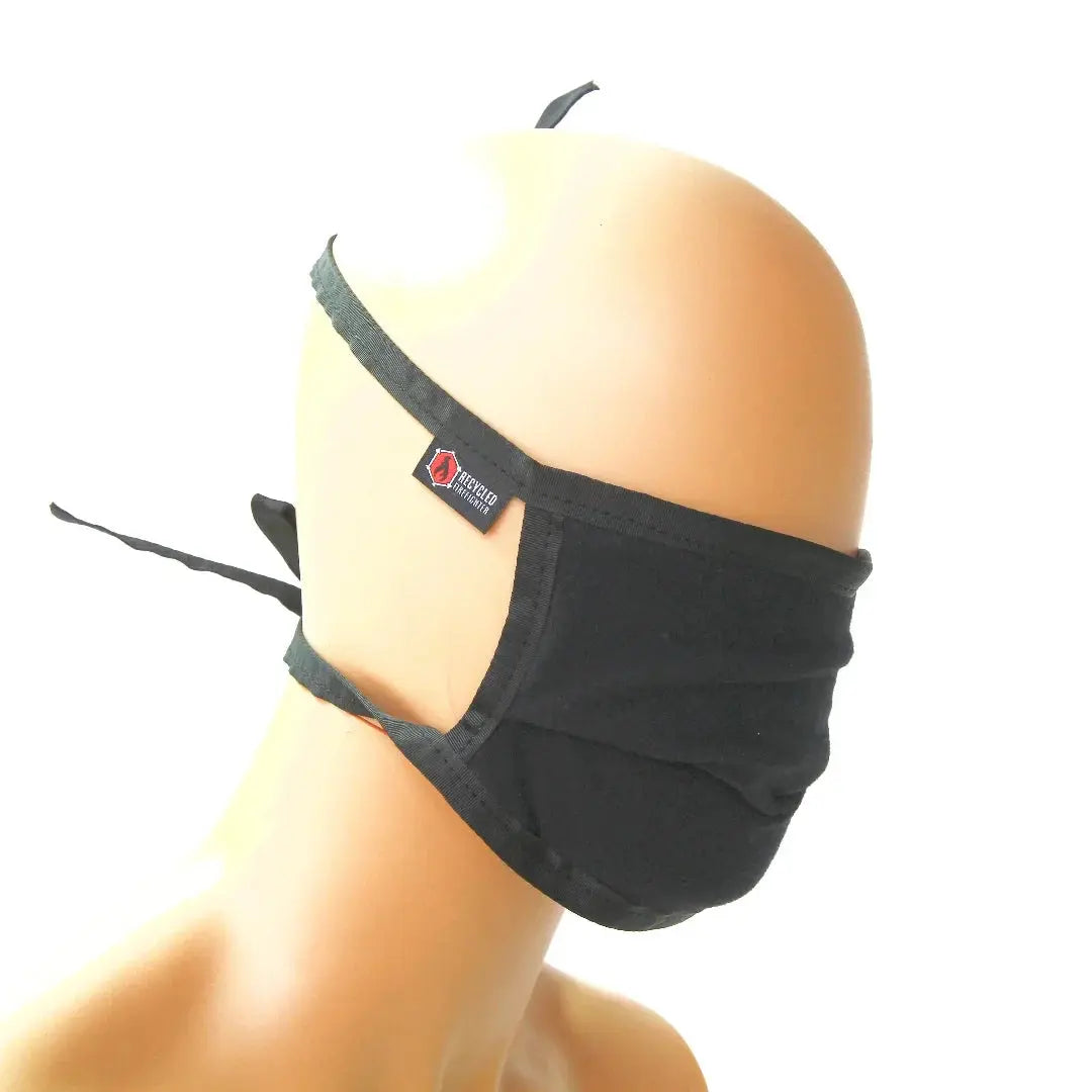 Black cotton face mask with tie-back straps and a brand tag.