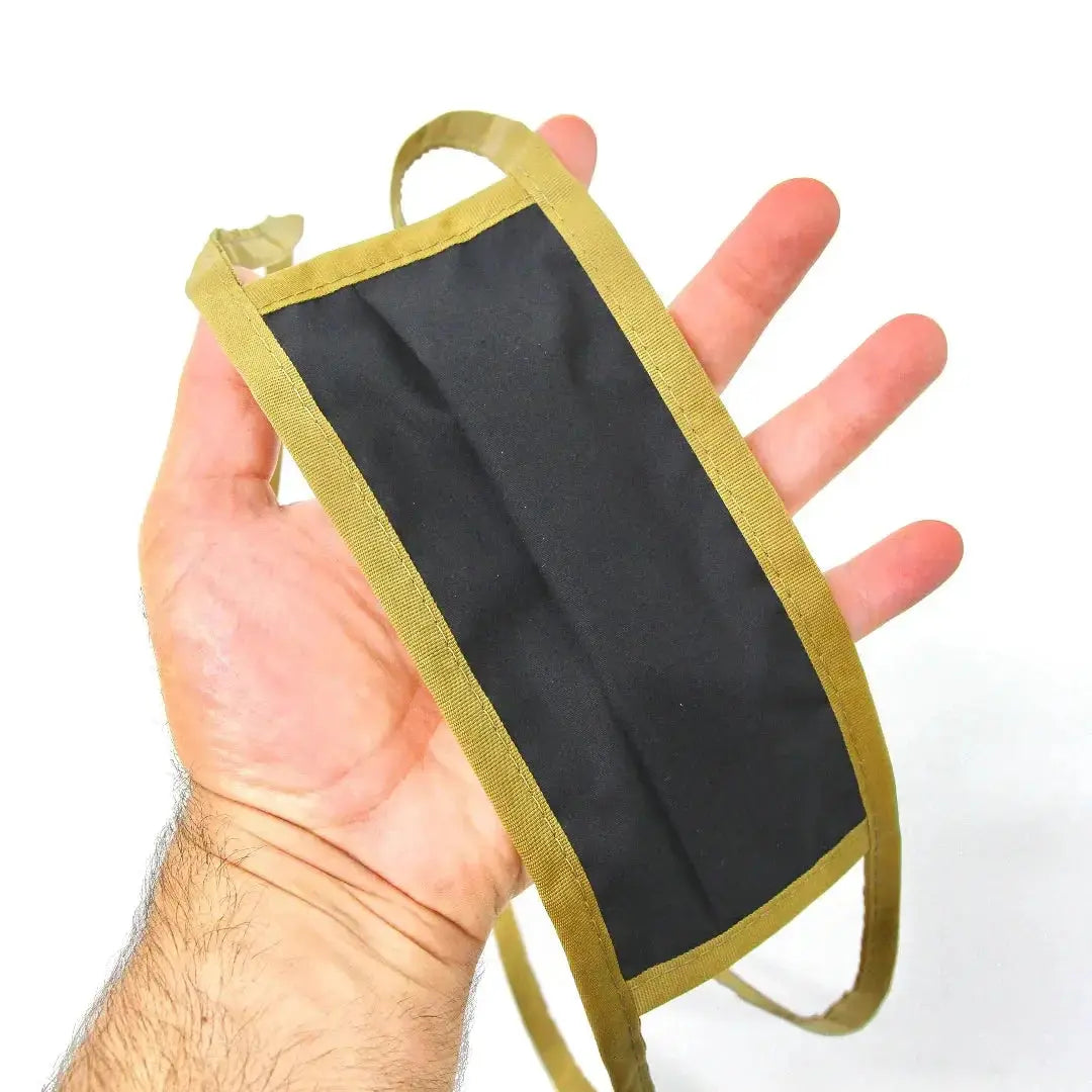 Black cotton mask with tan binding and adjustable nose wire held in a hand.