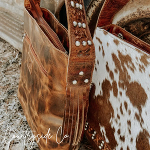 Brown cowhide leather purse with fringe and studded strap.