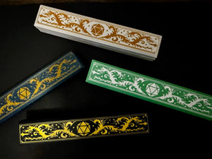 Customizable Adventurer dice boxes in white, blue, green, and black with gold or white filigree detail.
