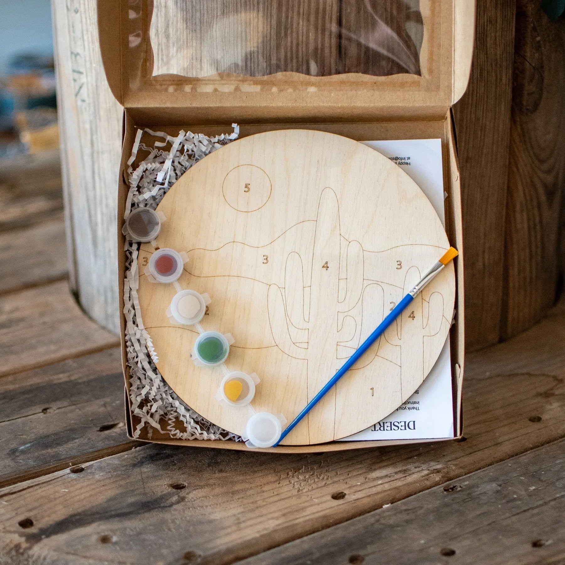 Wooden desert paint by number kit with cactus, paints, and brush in a box.