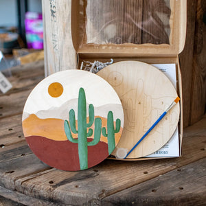 Wooden paint by number kit with desert landscape, cactus, sun, and brush.