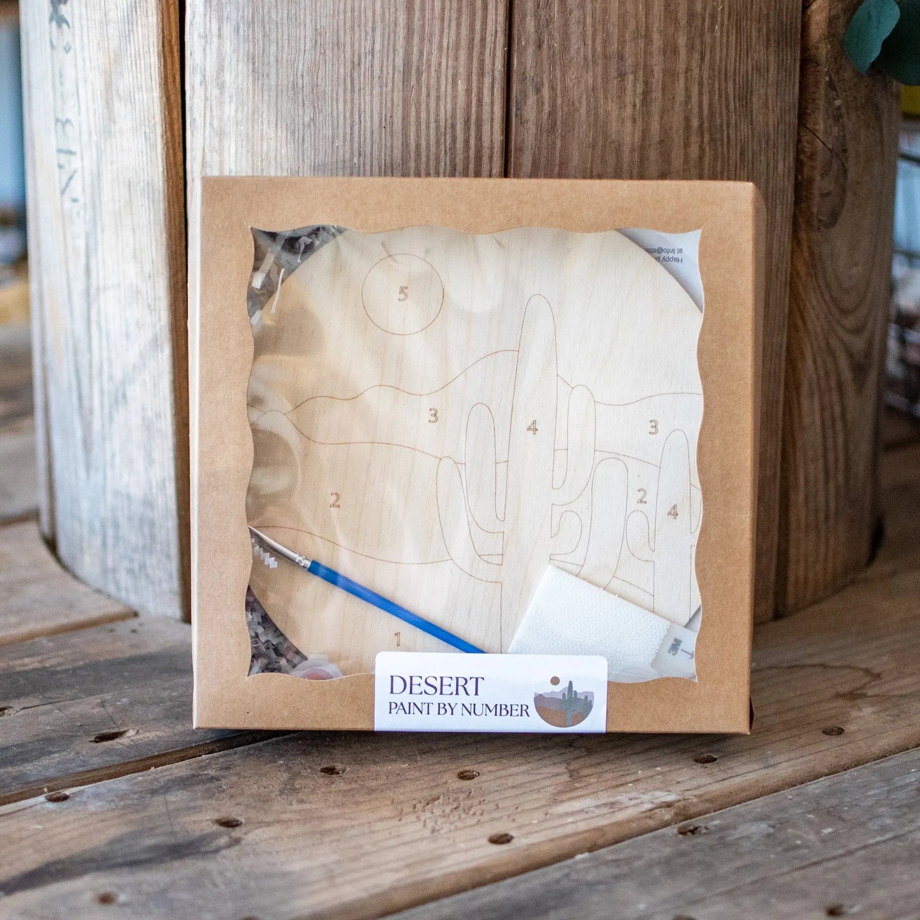 Desert paint by number kit with wooden disc and brush.