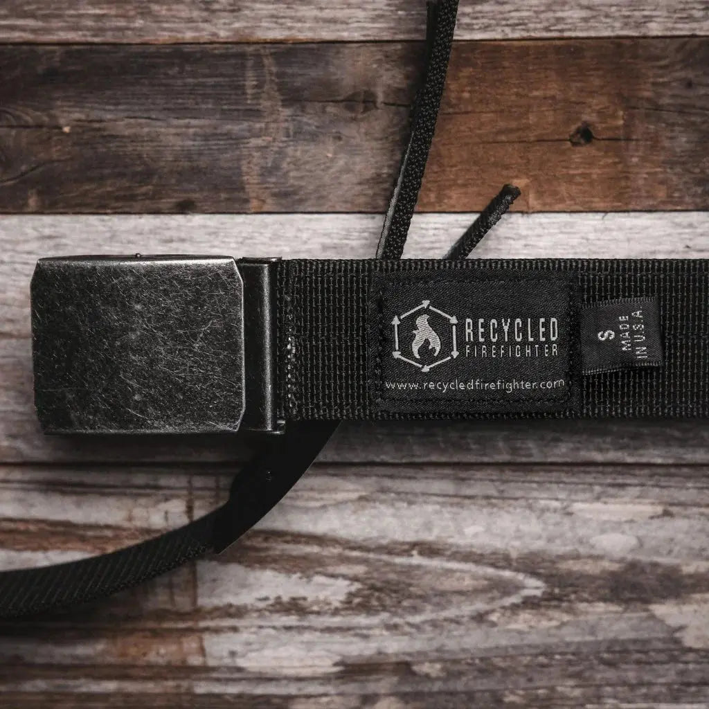 Black double layer EDC belt with metal buckle on a wooden background