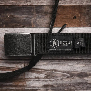 Black double layer EDC belt with metal buckle on a wooden background