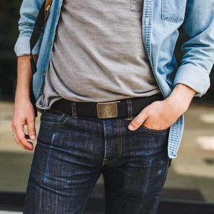 Black double layer EDC belt with a brass-colored friction buckle on dark denim jeans.