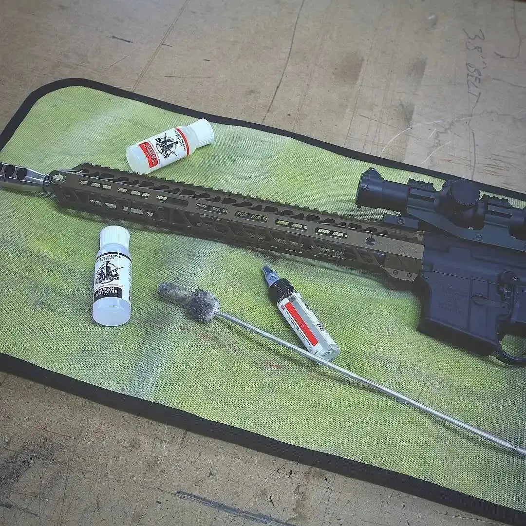 AR-15 rifle cleaning tools and supplies on a green drop zone mat.