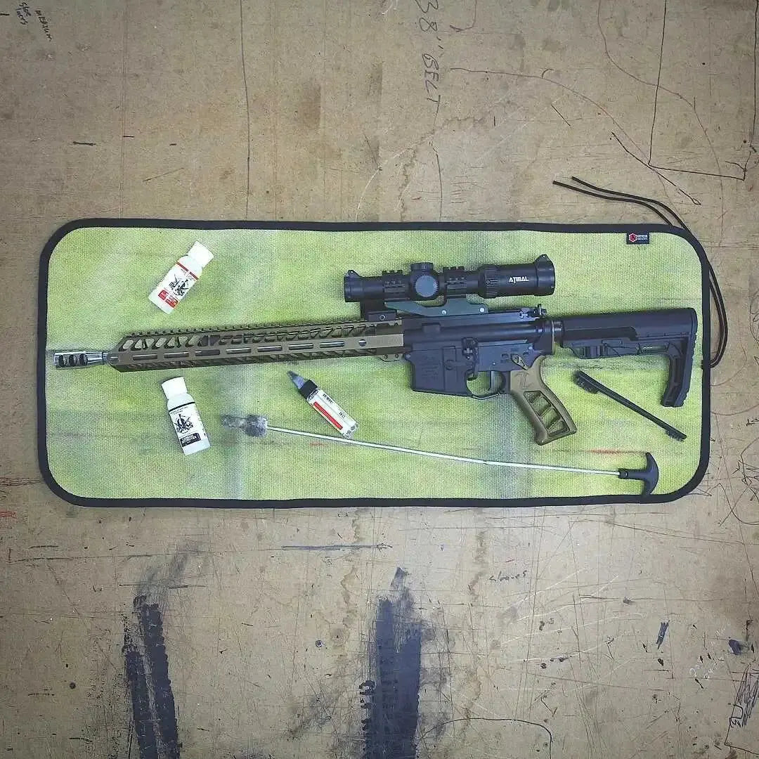 AR-style rifle and cleaning tools on a green fire hose mat.