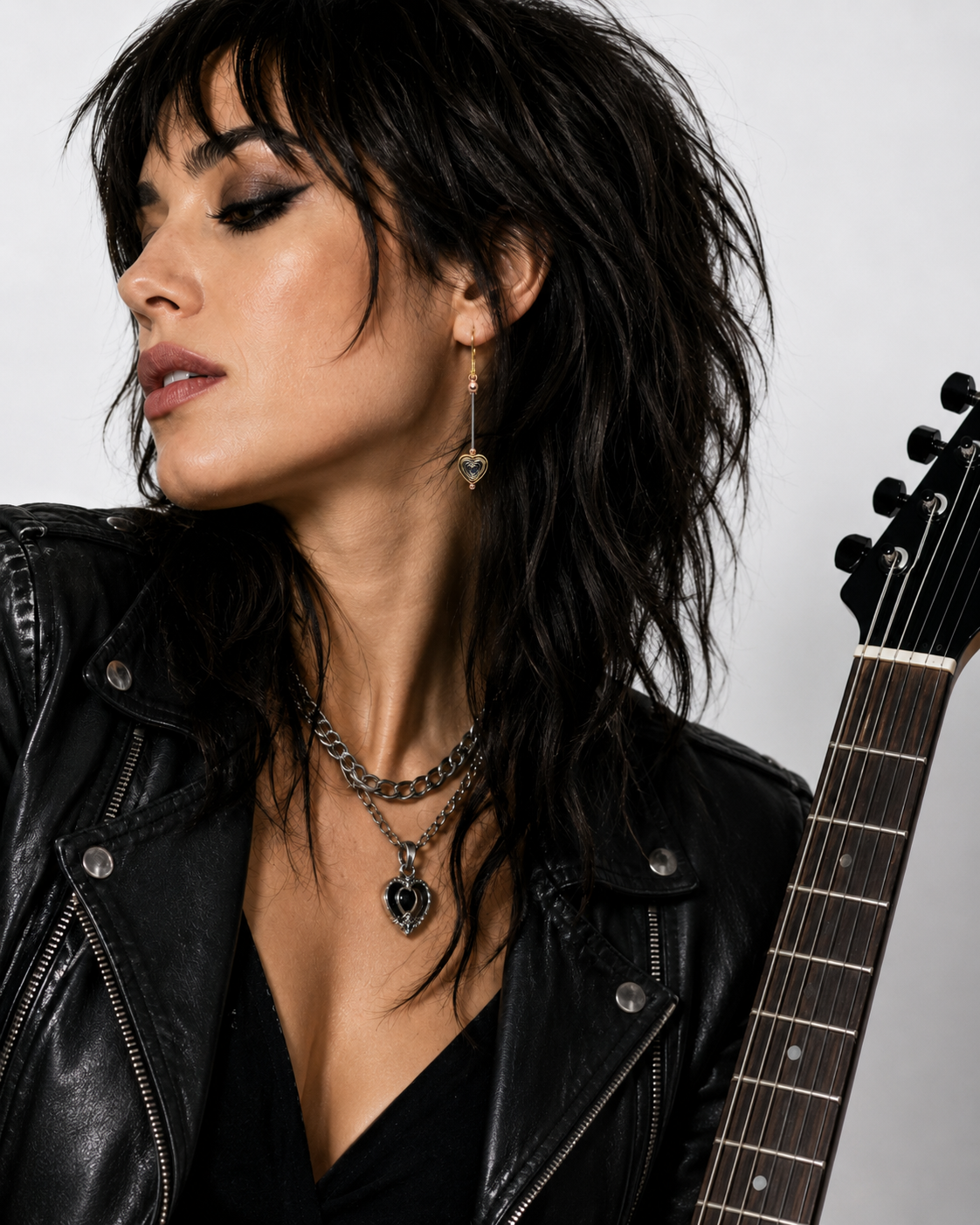 Woman with dark hair and leather jacket holding an electric guitar
