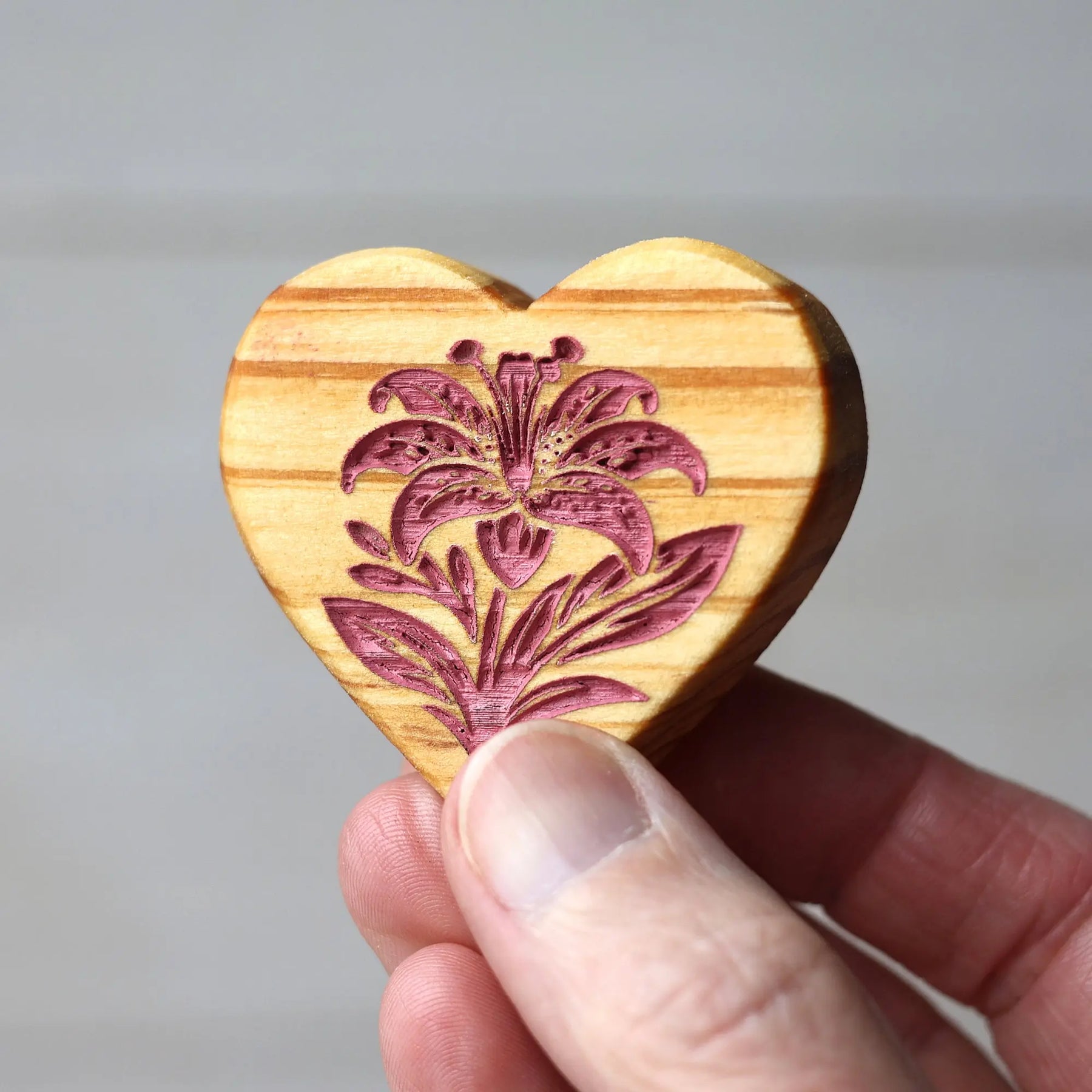 Wooden heart shape with engraved lily flower design.