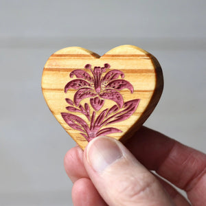 Wooden heart shape with engraved lily flower design.