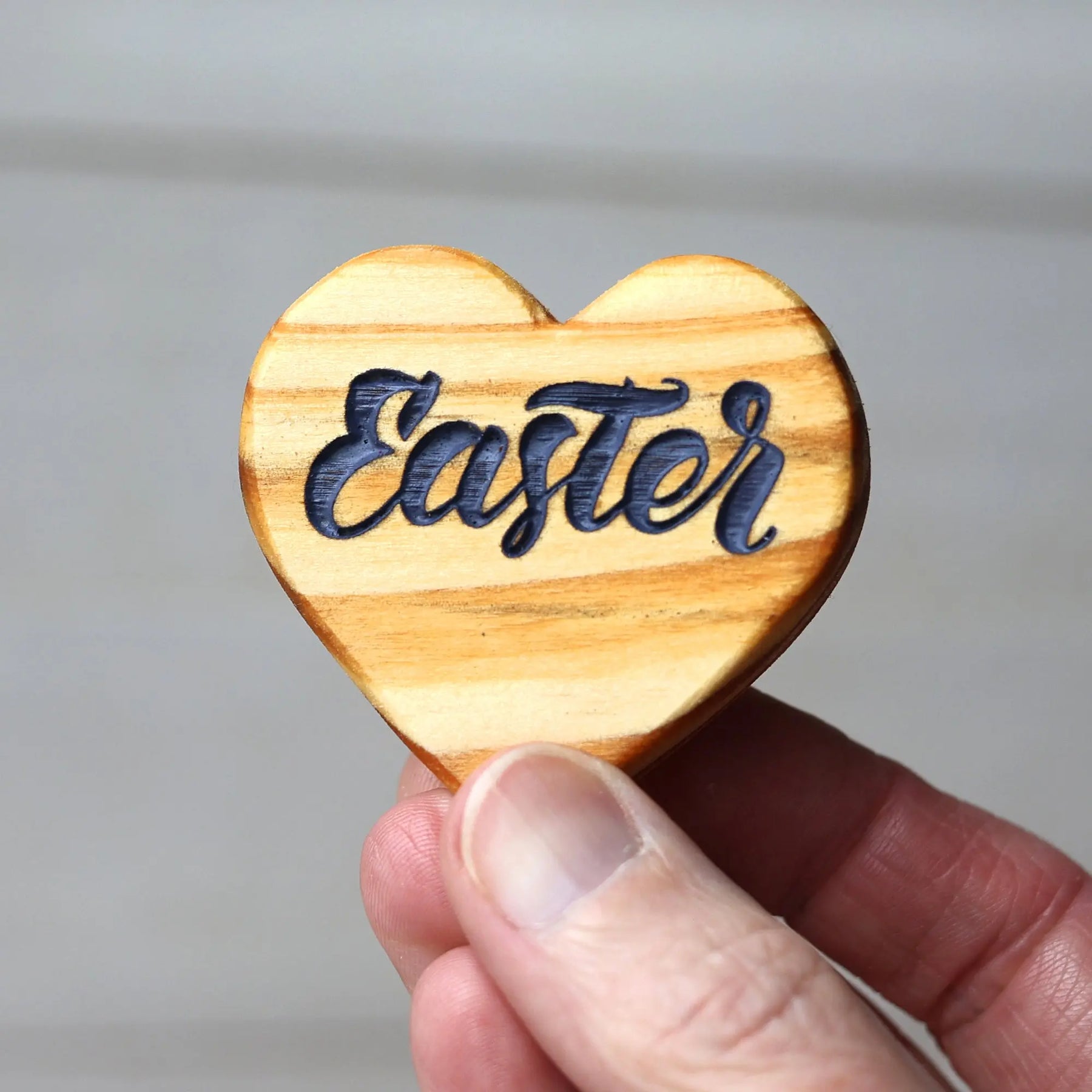 Wooden heart with the word "Easter" engraved in dark blue letters.