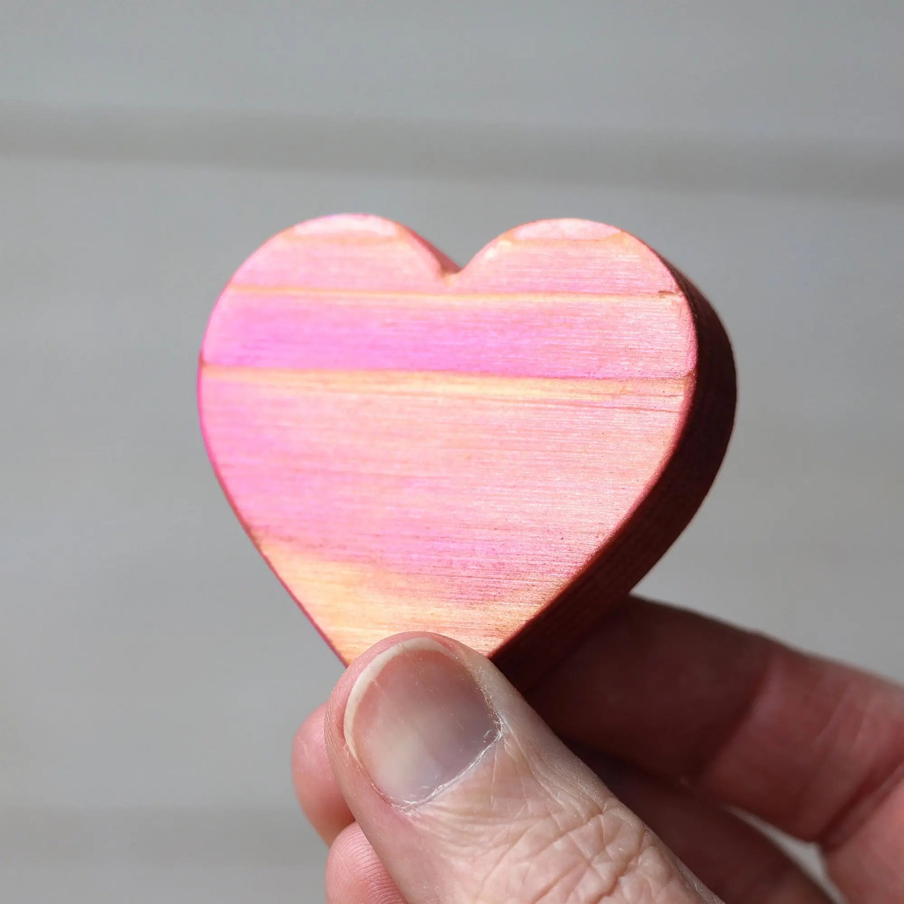 Pink wooden heart with wood grain held in hand